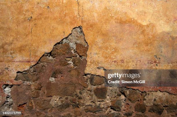 ancient cracked stucco and stone wall - steinwand stock-fotos und bilder