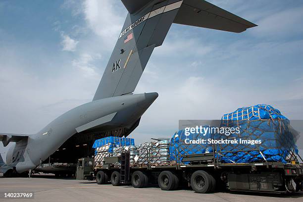 a japanese soldier marshals vehicles from a c-17 globemaster iii. - humanitarian aid stock-fotos und bilder