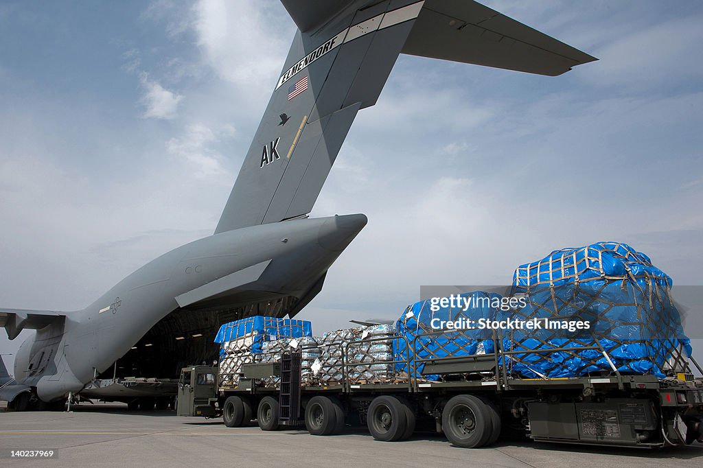 A Japanese soldier marshals vehicles from a C-17 Globemaster III.