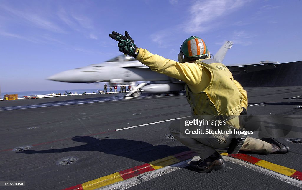 A shooter signals the launch of an F/A-18 Super Hornet.