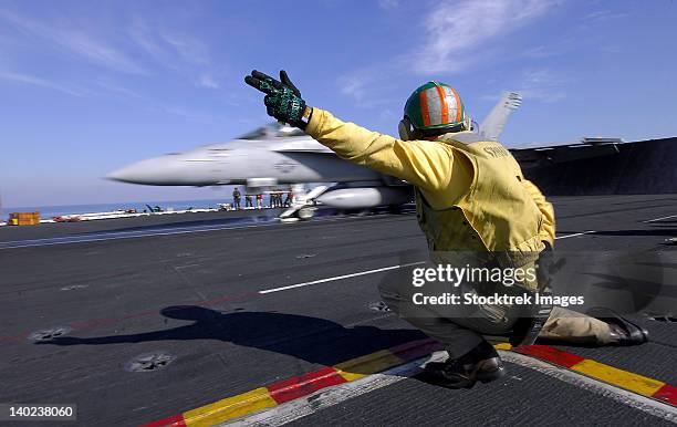 a shooter signals the launch of an f/a-18 super hornet. - war on terror stock-fotos und bilder