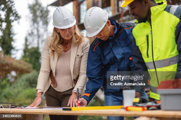 construction workers and female architect planning at construction site - bodyguard stock pictures, royalty-free photos & images
