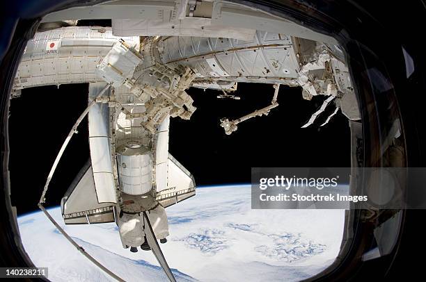 the docked space shuttle discovery and dextre. - iss window stock pictures, royalty-free photos & images