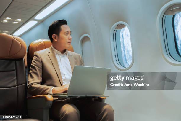 young handsome businessman with notebook sitting inside an airplane. - business person ipad travel stock-fotos und bilder