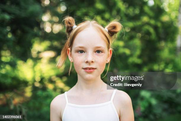 porträt eines rothaarigen mädchens mit sommersprossen auf sommerlichem, verschwommenem hintergrund. fröhliche und glückliche kindheit - girl portrait stock-fotos und bilder