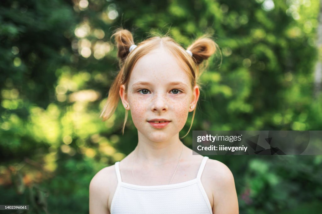 Retrato de chica pelirroja con pecas sobre fondo borroso de verano. Infancia alegre y feliz