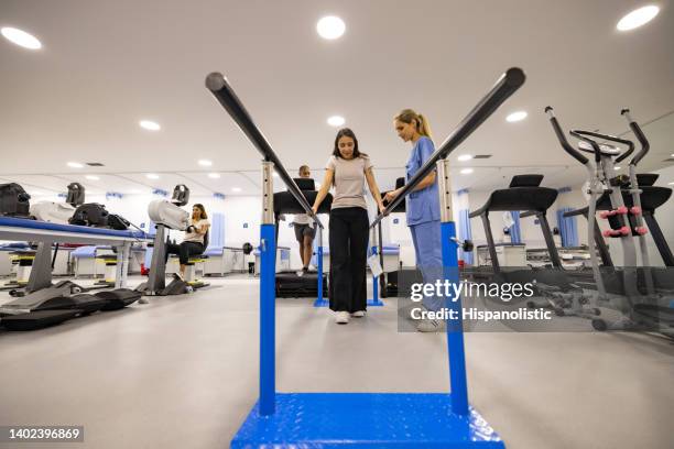 woman in physiotherapy walking on the parallel bars - afkickcentrum stockfoto's en -beelden