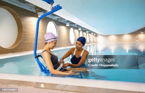 paziente che entra in piscina su una sedia di sollevamento per la sua idroterapia - issare foto e immagini stock