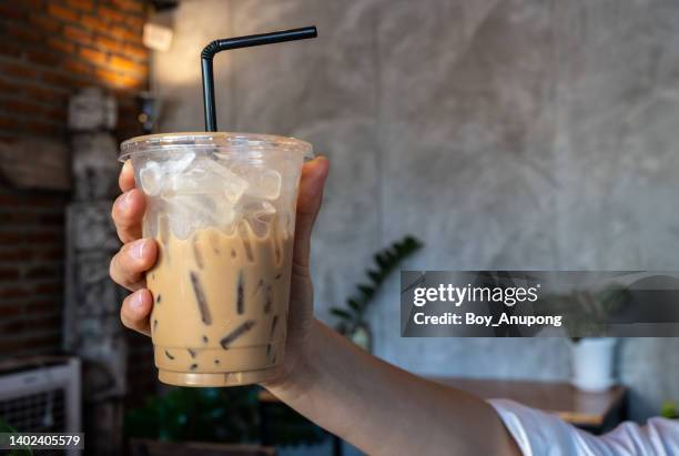 someone hand holding a plastic cup of iced milk coffee. - paglia foto e immagini stock