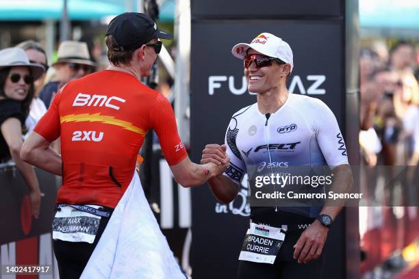 Braden Currie of New Zealand crosses the line finishing second and is congratulated by winner Max Neumann of Australia in Ironman Cairns on June 12,...