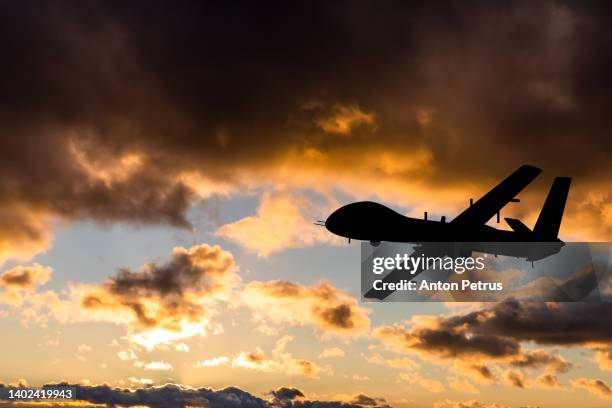 military unmanned aerial vehicle at sunset. combat drone in military conflicts - op afstand bediend stockfoto's en -beelden