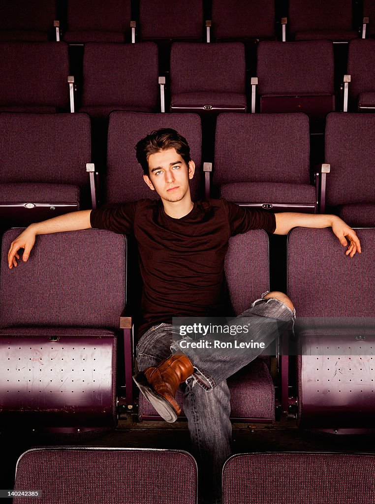 Young man lounging in theatre seats, portrait