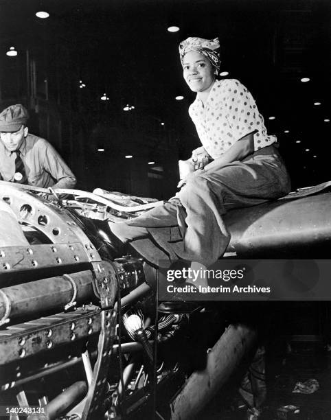 View of a female riveter, part of the wartime labor force, working on the fabrication of an airplane, at Lockheed Aircraft Corporationi, in Burbank,...