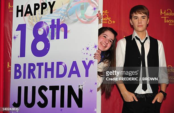 Alicia Purdom winner of Madame Tussauds Hollywood contest to find Justin Bieber's biggest fan, peeks from behind a giant birthday card beside the...