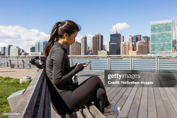 asian girl texting, preparing for working out outdoors new york city - long island city stock pictures, royalty-free photos & images