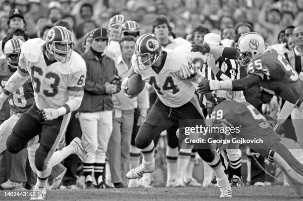 Running back John Riggins of the Washington Redskins runs behind the blocking of offensive tackle Fred Dean as he is pursued by linebackers Bob...