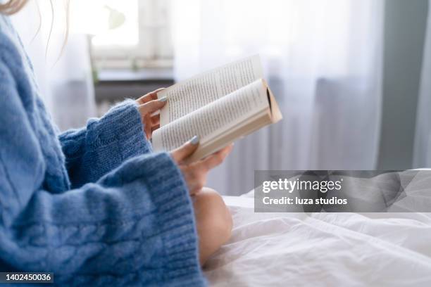 leer un libro en la cama - libro en rústica fotografías e imágenes de stock
