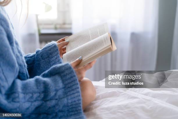 reading a book in bed - paperback stock pictures, royalty-free photos & images