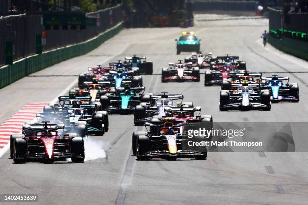 Charles Leclerc of Monaco driving the Ferrari F1-75 locks a wheel under braking as he battle for track position with Sergio Perez of Mexico driving...