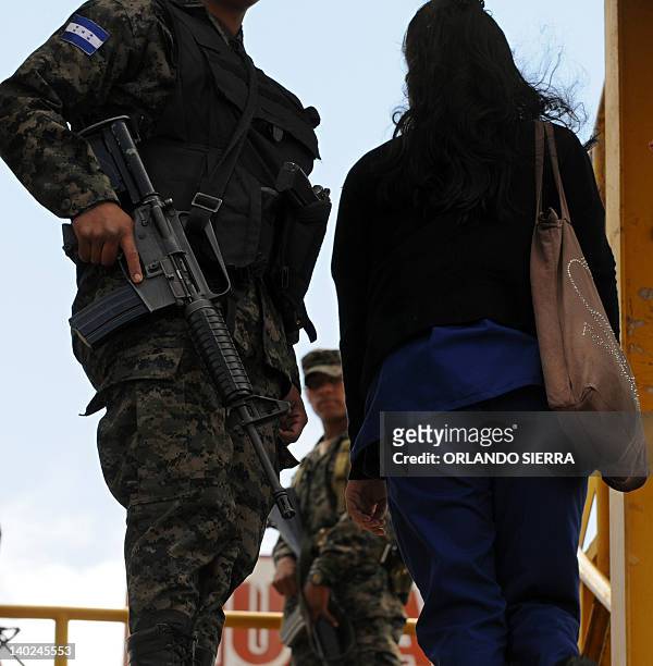 Soldiers of the Honduran Army armed with an M-16 rifle provide security at a bus stop in Tegucigalpa on March 1, 2012. To combat the increasing...
