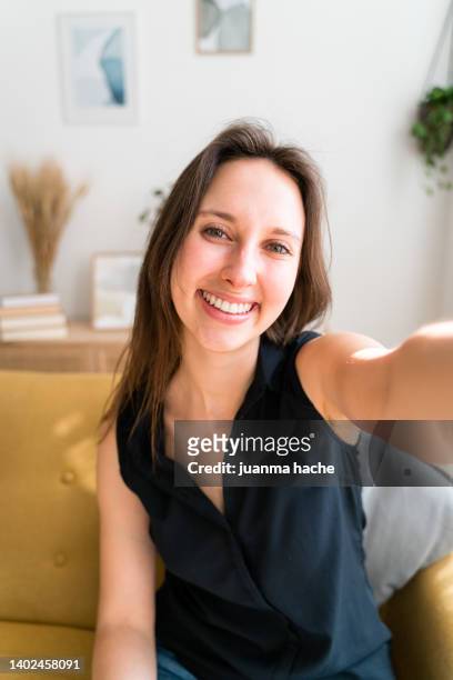 happy woman smiling while taking a selfie at home. - selfie frau stock-fotos und bilder