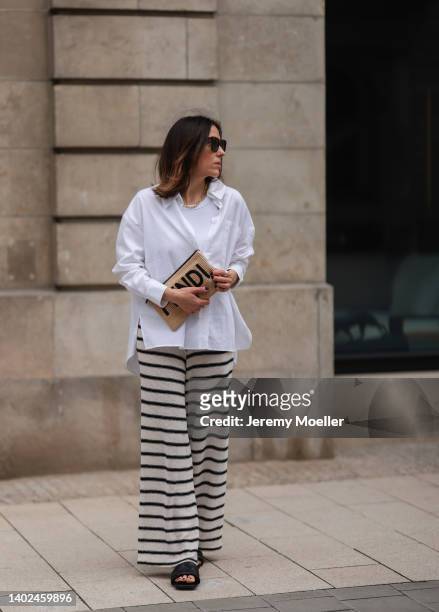 Elise Seitz seen wearing a brown Celine sunglasses, a white shirt blouse from Soho Studios, a white/black stripped pants from Zara, black leather...