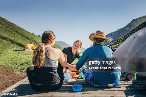 three female tourists have lunch while hiking in the mountains. - inspiring women luncheon ストックフォトと画像