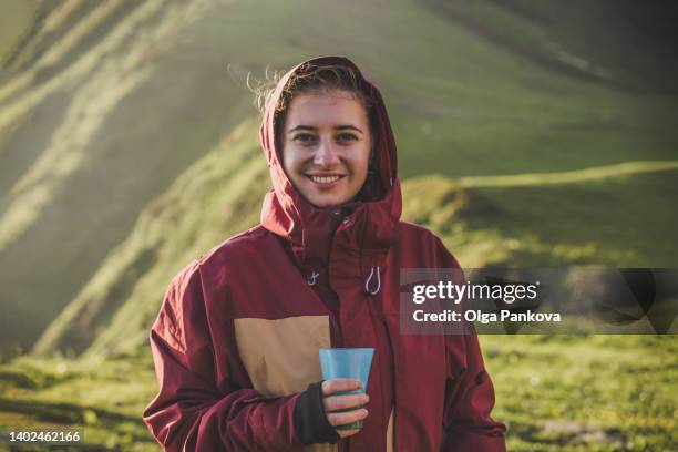 female tourist drinks water at a rest stop during a hike in the mountains. - pioneer stock pictures, royalty-free photos & images