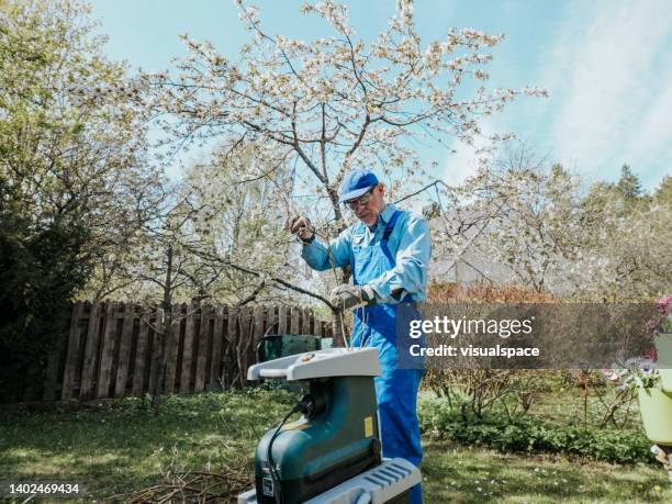senior man using electric shredder in garden - wood chipper stock pictures, royalty-free photos & images