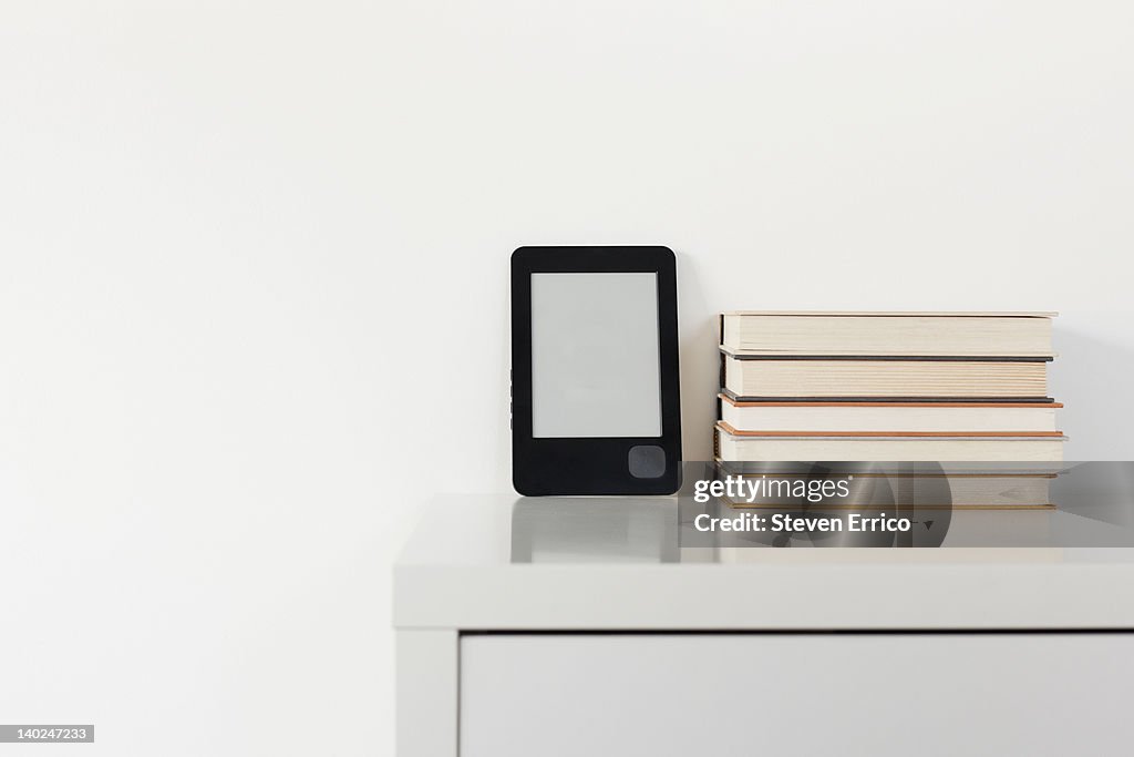 Electronic book reader next to traditional books