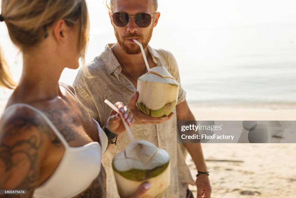 Caucasian couple drinking coconut on the beach