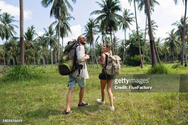 rear-view of adventurous couple exploring the rainforest - 背包客 個照片及圖片檔