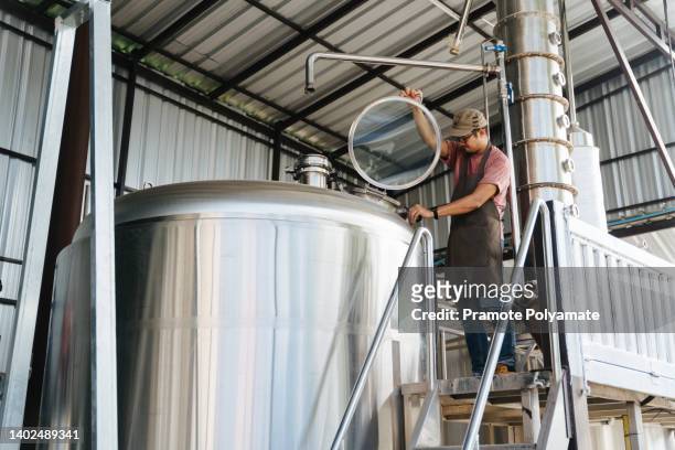 a male brewer controlling beer fermentation process at his craft beer factory. - fermenting tank stock pictures, royalty-free photos & images