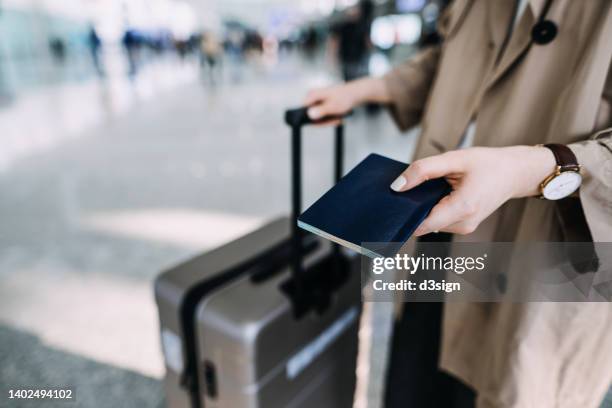 cropped shot, mid-section of young woman carrying suitcase and holding passport at airport terminal. ready to travel. travel and vacation concept. business person on business trip - boarding plane stock pictures, royalty-free photos & images