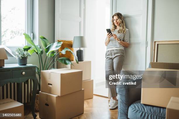 mujer madura con cajas de mudanza en un nuevo hogar - mobile first fotografías e imágenes de stock