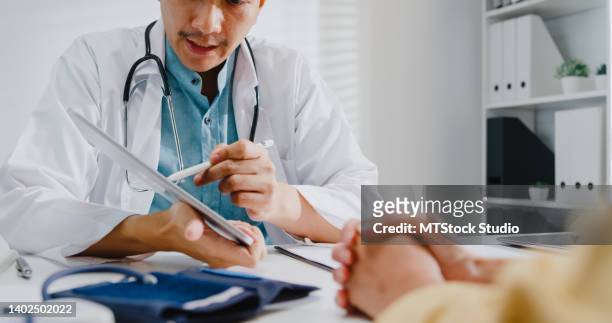 close up of mature asian man doctors medical results during consultation on tablet computer with woman patient in health clinic. - ipad close up stock pictures, royalty-free photos & images