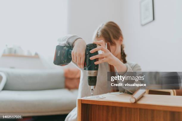 young woman making a diy furniture improvement - elektrisch gereedschap stockfoto's en -beelden