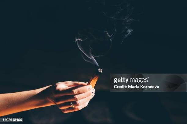 woman holding palo santo stick on dark background. - aromatherapy stock pictures, royalty-free photos & images
