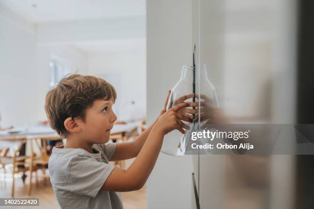 boy filling glass with water from refrigerator - girl filling water glass stock pictures, royalty-free photos & images