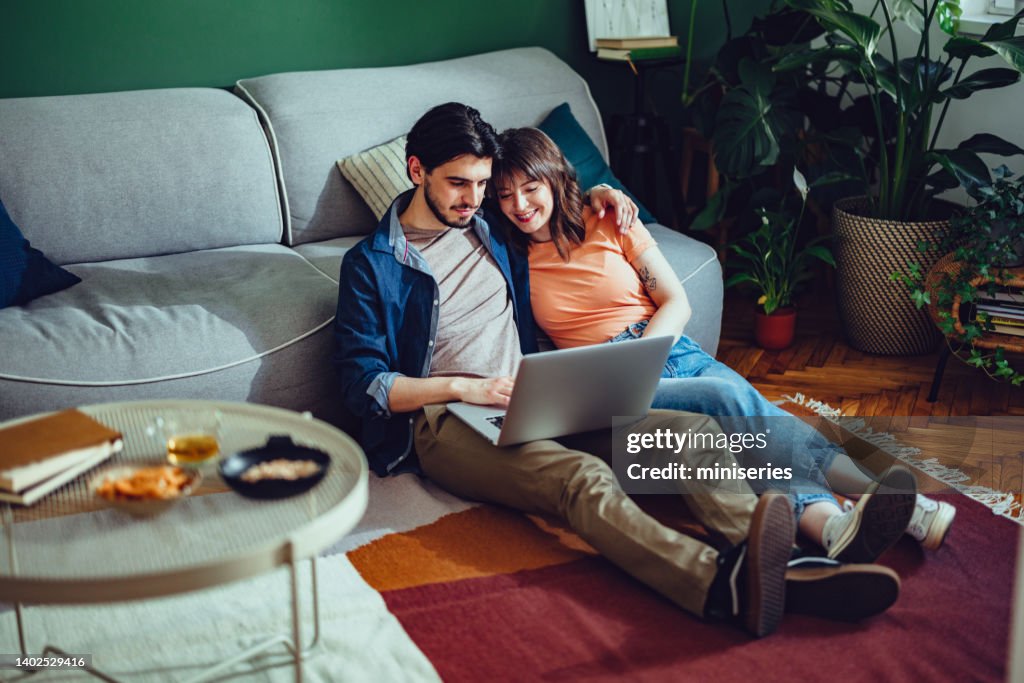 Couple Using One Computer Smiling Couple Using A Laptop Computer Together At Home High-Res Stock ...