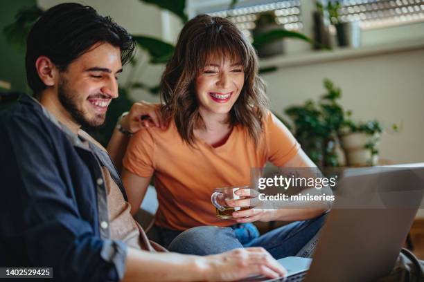 cheerful couple having fun using a laptop computer together at home - adult braces stock pictures, royalty-free photos & images