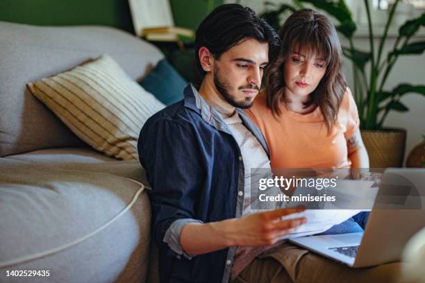 ernsthaftes paar, das rechnungen zu hause bezahlt - wohngebäudeversicherung stock-fotos und bilder