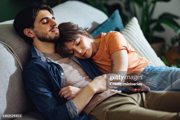 loving couple sleeping together on a sofa - tired couple stock pictures, royalty-free photos & images