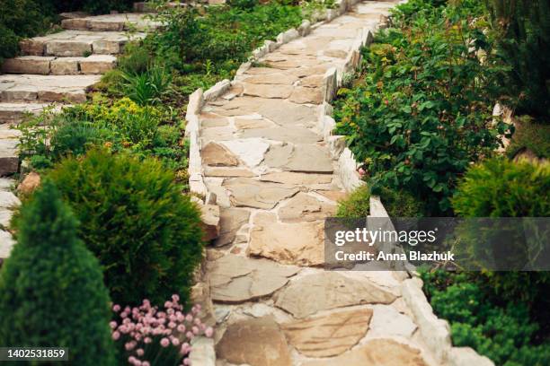 stone walkway in garden made of big yellow stones, garden landscaping design. - landscape tree and flowers stockfoto's en -beelden