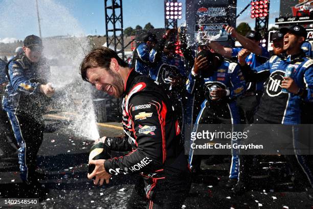 Daniel Suarez, driver of the Onx Homes/Renu Chevrolet, and crew celebrate by spraying champagne in victory lane after winning the NASCAR Cup Series...
