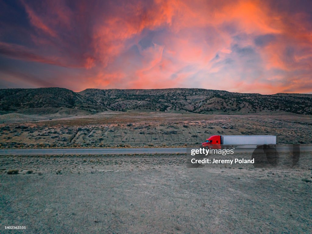 Aerial Drone Shot of a Red Semi Truck on the Highway with a Colorful Sunset