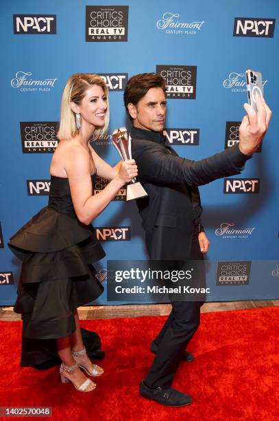 Kelly Rizzo, who accepted The Impact Award on behalf of the late Bob Saget, and John Stamos pose for a selfie photo during the Fourth Annual Critics...