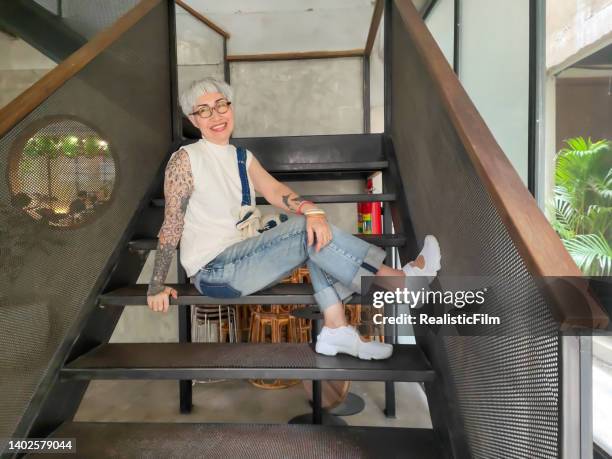 senior woman sitting on staircase with a smile - old woman tattoos stock pictures, royalty-free photos & images