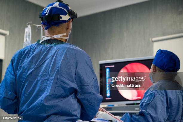 two neurosurgeons monitor the surgery from a digital screen - endoscope stock pictures, royalty-free photos & images