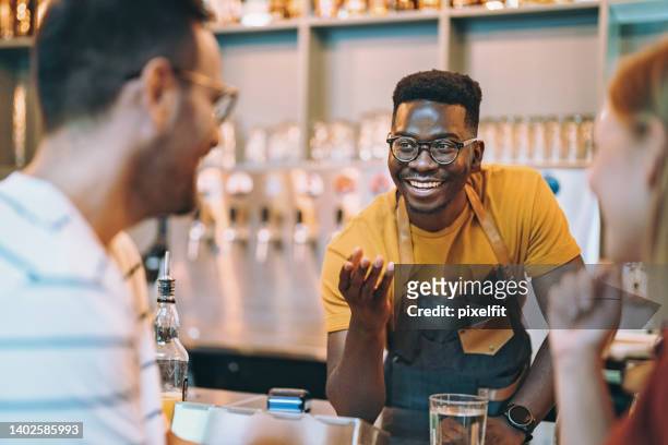 bartender talking with visitors - bartender stock pictures, royalty-free photos & images